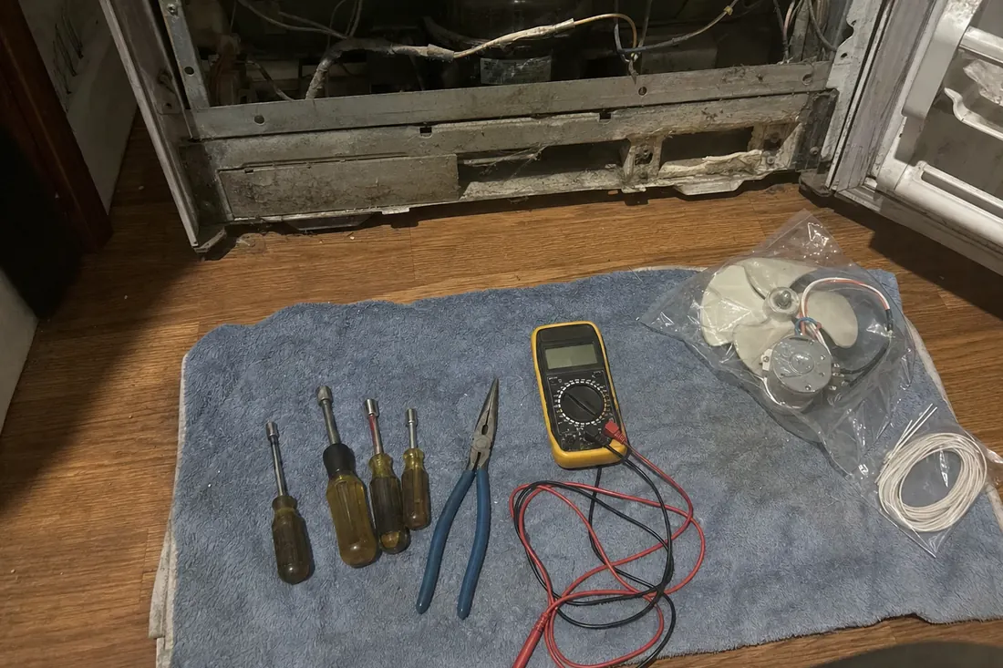 Flat-lay of nut drivers, pliers, a multimeter and a bagged fan motor on a towel, the multimeter visible in the picture - What Salt Air Does to a Condenser Coil